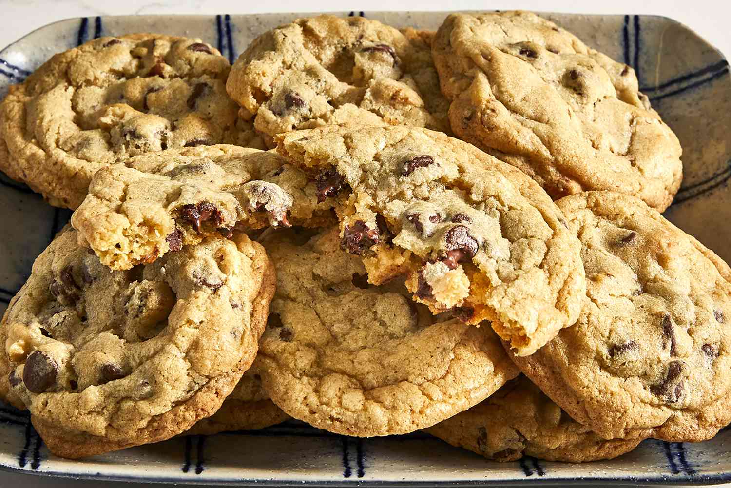 A close up view of a pile of best ever chocolate chip cookies with one broken in half
