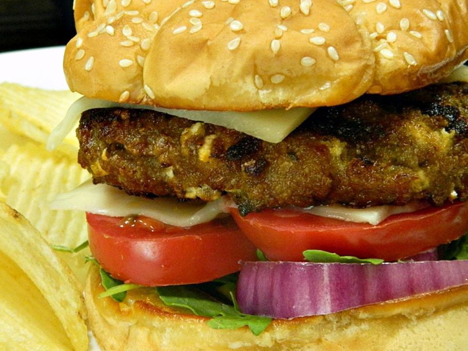 Close up view of Pesto Turkey Burgers served with potato chips on a plate