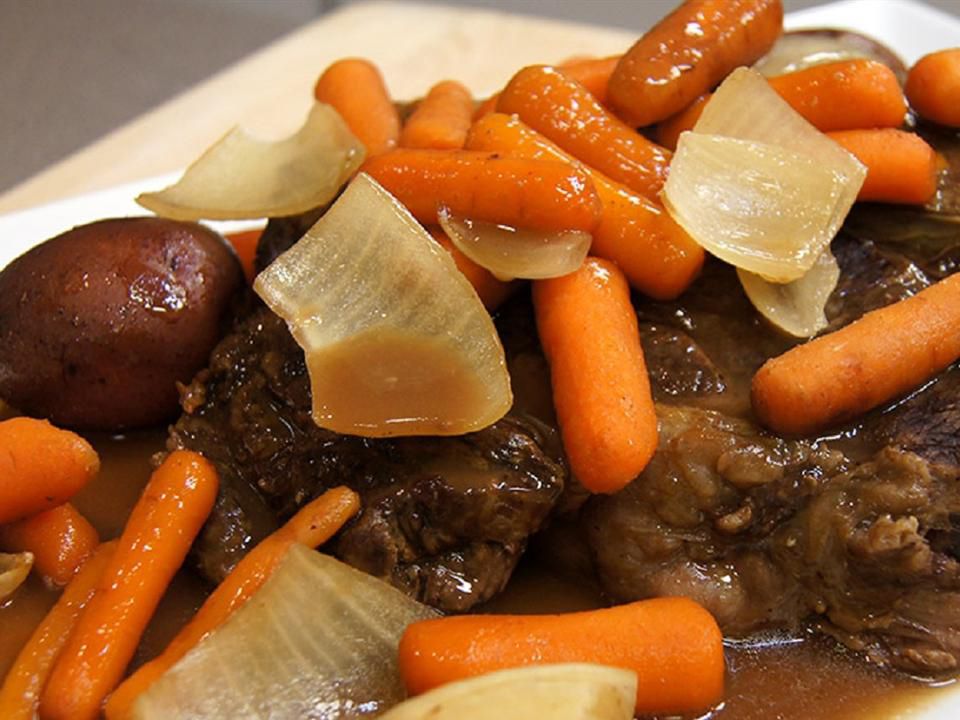 Close up view of Slow Cooker Roast Beef in its own Gravy served with carrots, onions and potatoes on a platter