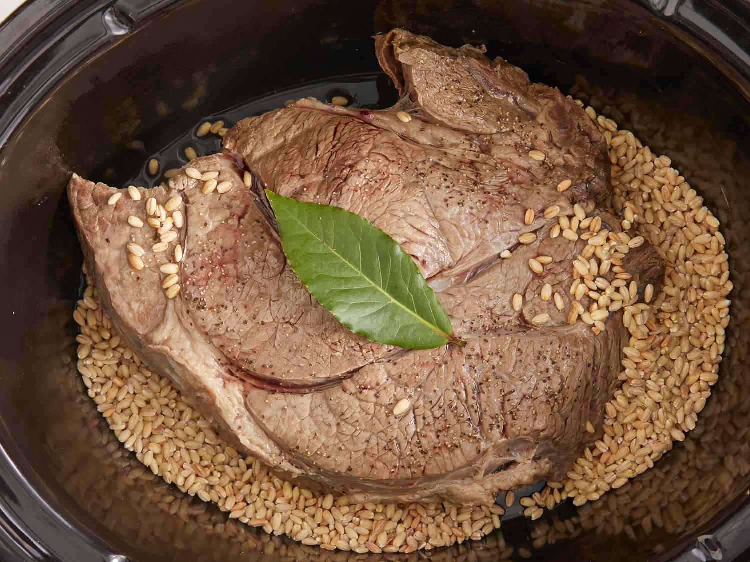 Overhead shot of a slow cooker with meat and barley
