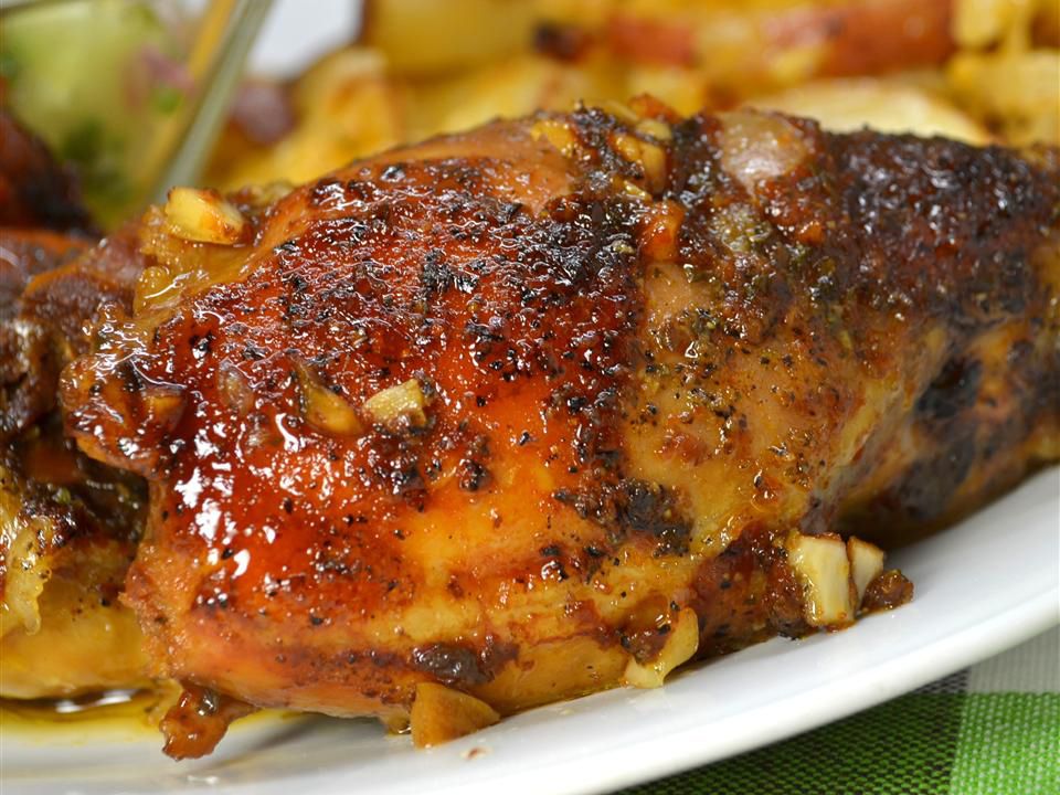 Close up view of a Honey-Garlic Slow Cooker Chicken Thigh served with potatoes, on a white plate 