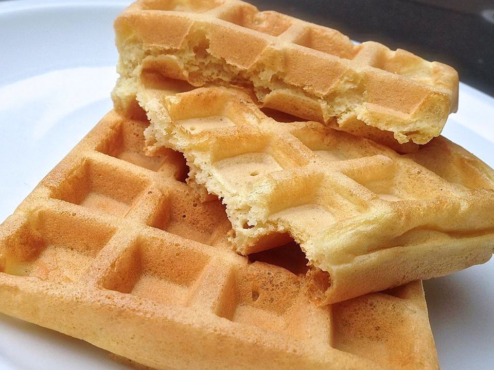 Close up view of a pile of Gluten-Free Waffles on a white plate