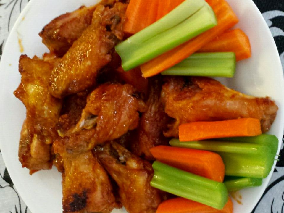 Close up view of Oven-Baked Chicken Wings with buffalo sauce, served with carrots and celery