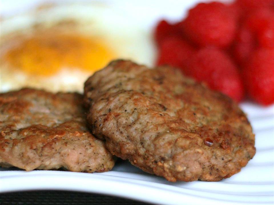 Close up view of Homemade Turkey Breakfast Sausage on a platter with eggs and berries