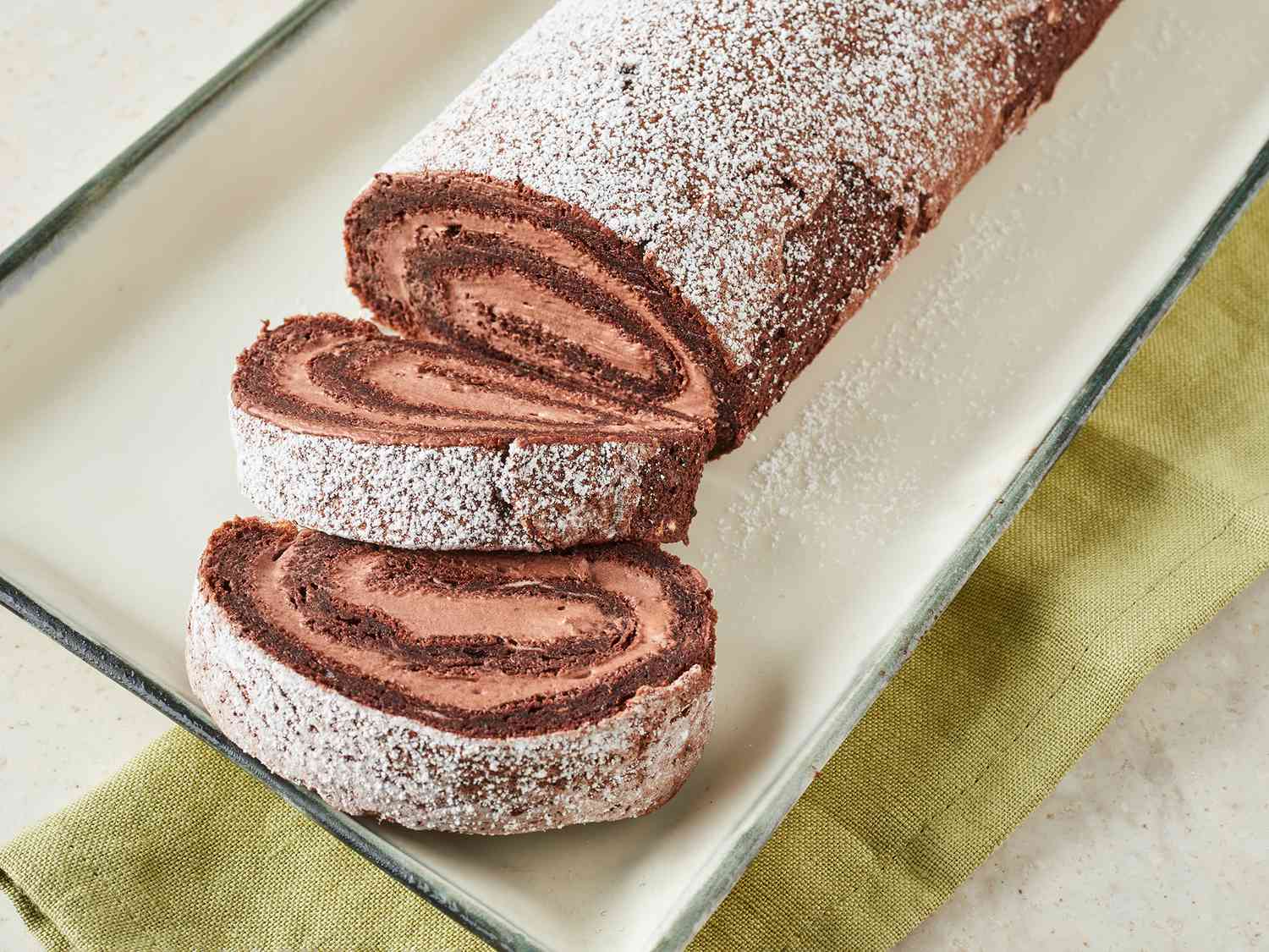 Close up on Buche de Noel on a platter with two pieces sliced.