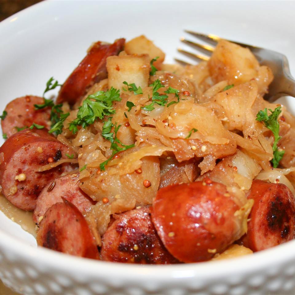 Close up view of Smoked Sausage with Potatoes, Sauerkraut & Ale garnished with fresh herbs