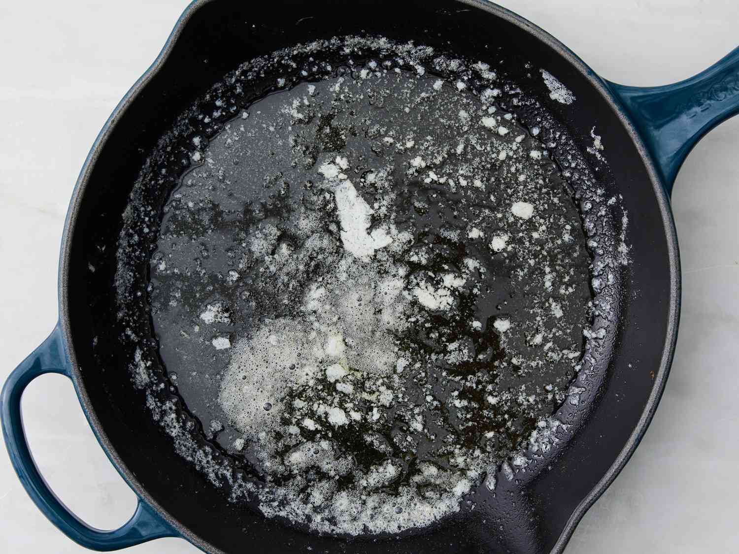 A top down view of butter melting in a skillet.