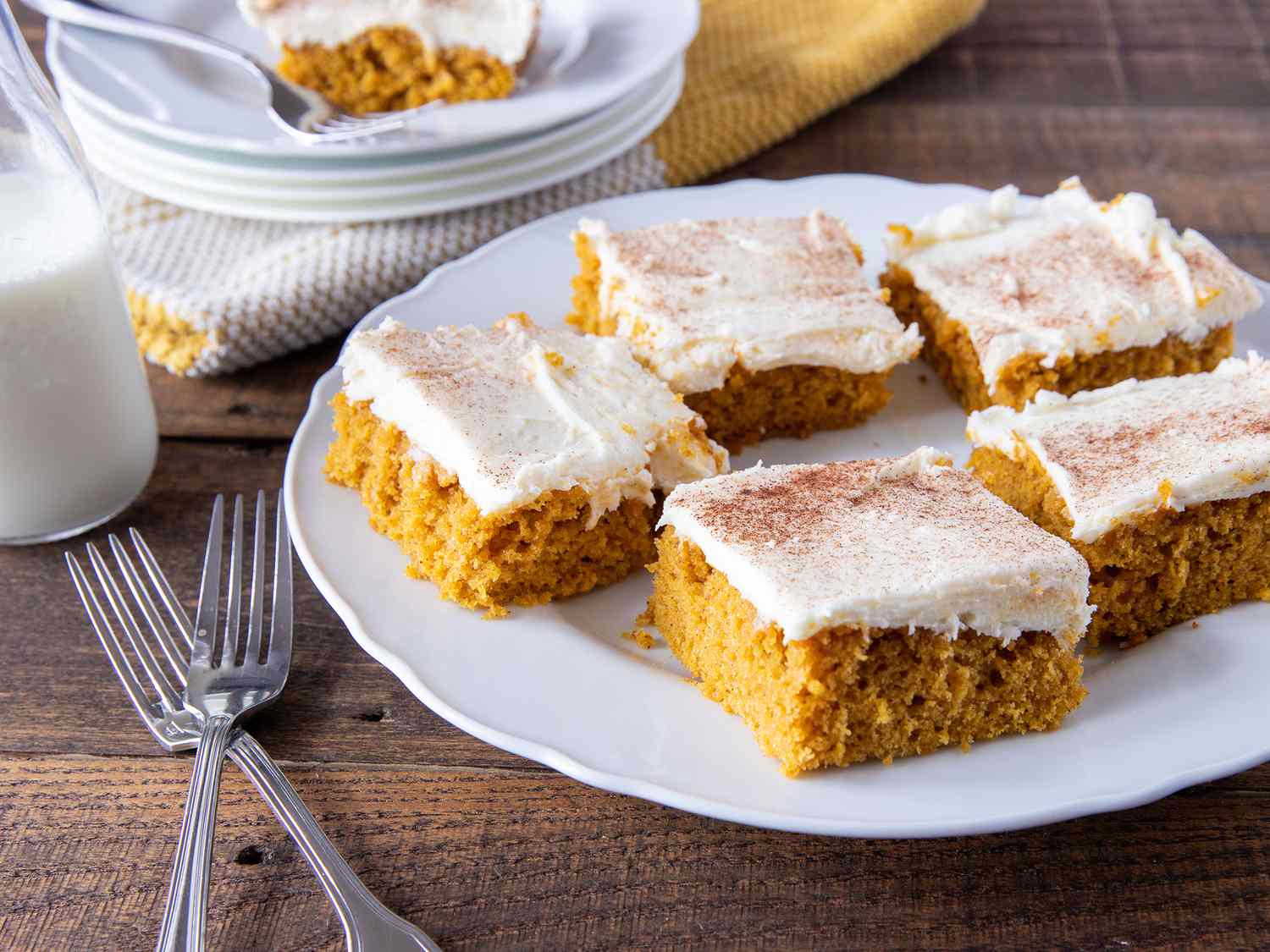 Low angle shot of pumpkin bars with cream cheese frosting on a serving plate