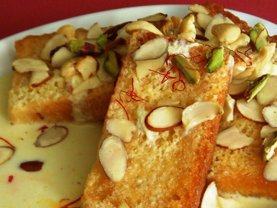 Close up view of Shahi Tukra (Indian Bread Pudding) garnished with nuts on a plate