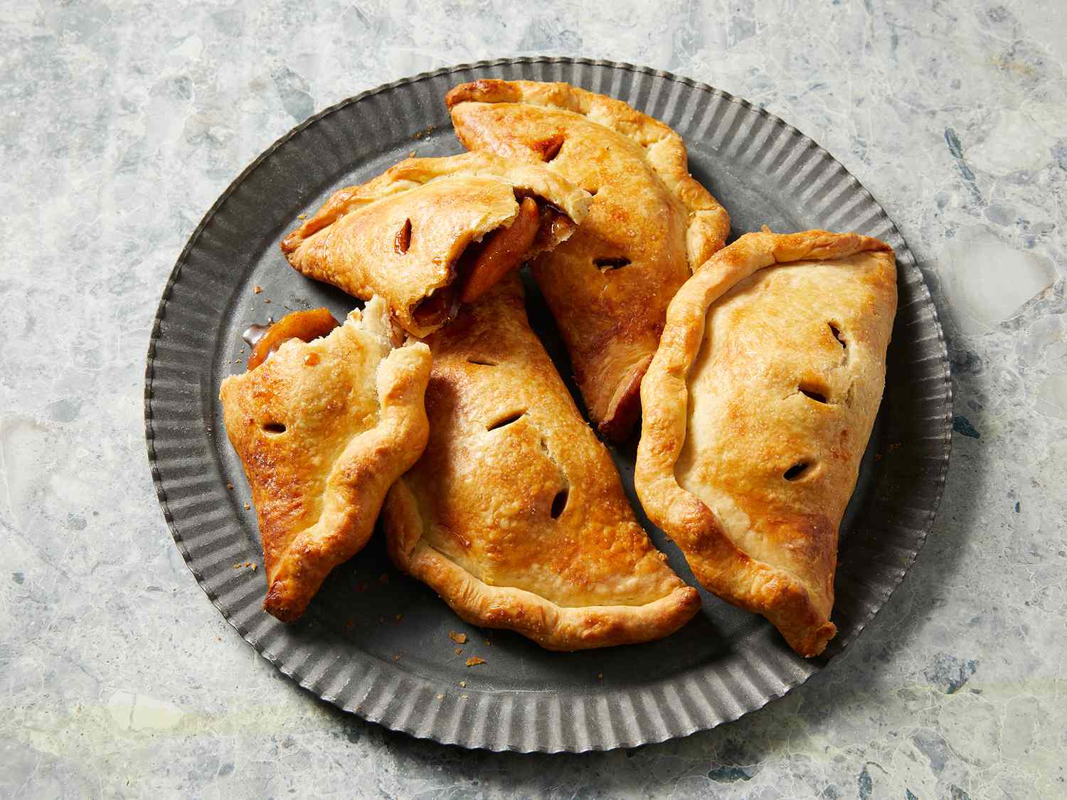 Close up on a plate of a few apple hand pies with one cut in half.
