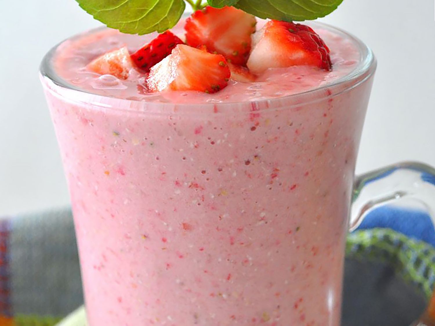 A super close up view of a strawberry oatmeal smoothie garnished with chopped strawberries