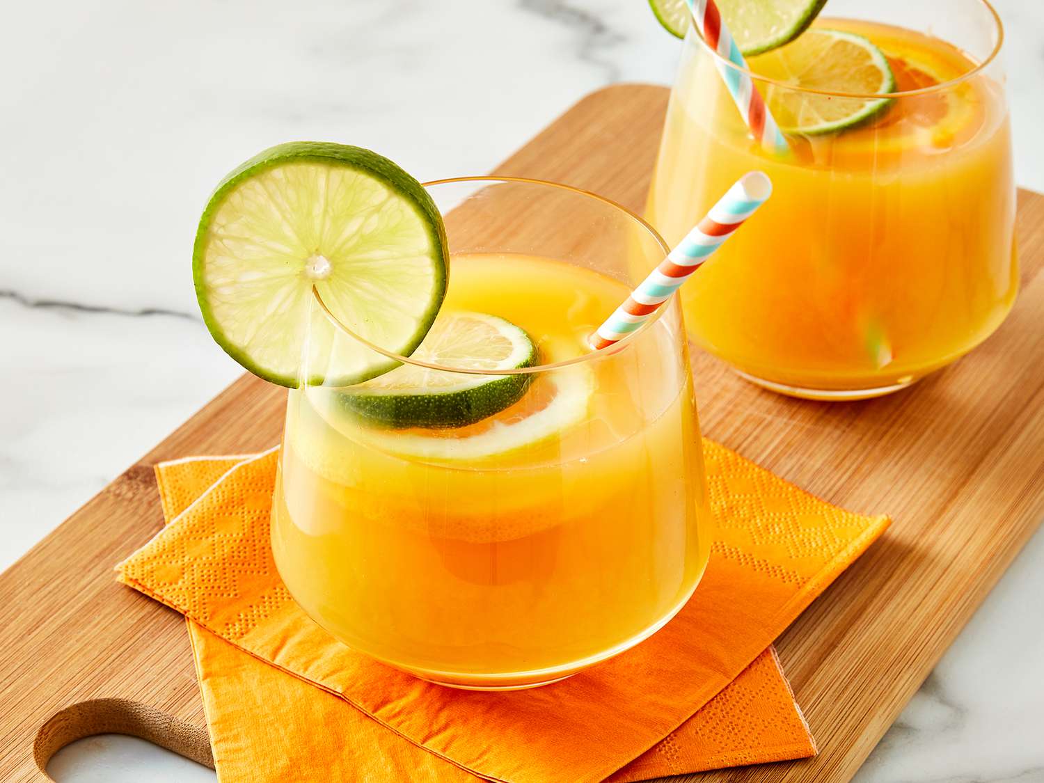 High angle looking at two glasses of Jamaican rum punch, garnished with lime slices.