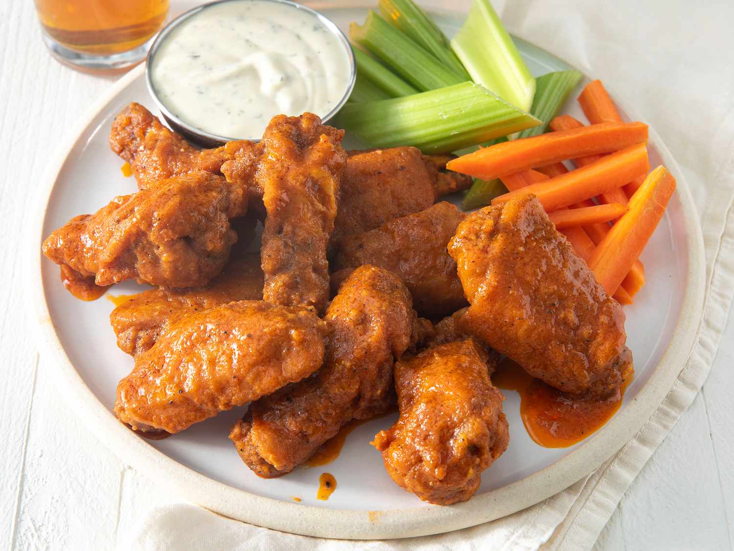 High angle looking at a plate of buffalo chicken wings, with a side of ranch, carrots and celery.