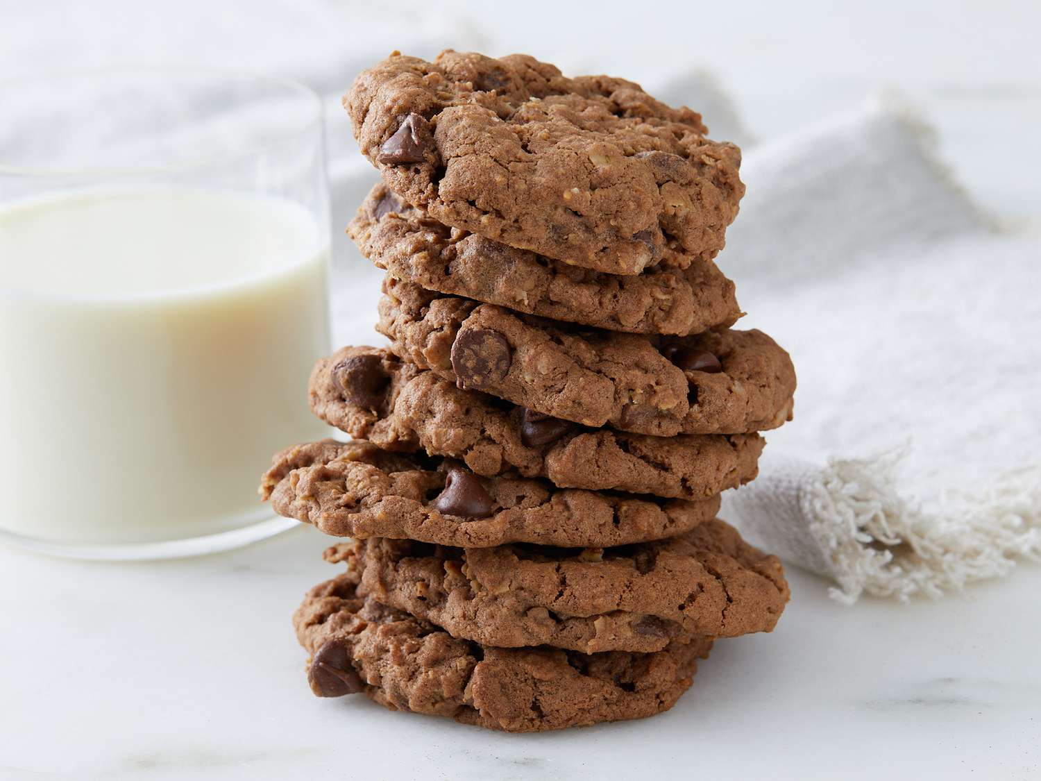 Close up on a tall stack of chocolate oatmeal cookies with a side of milk