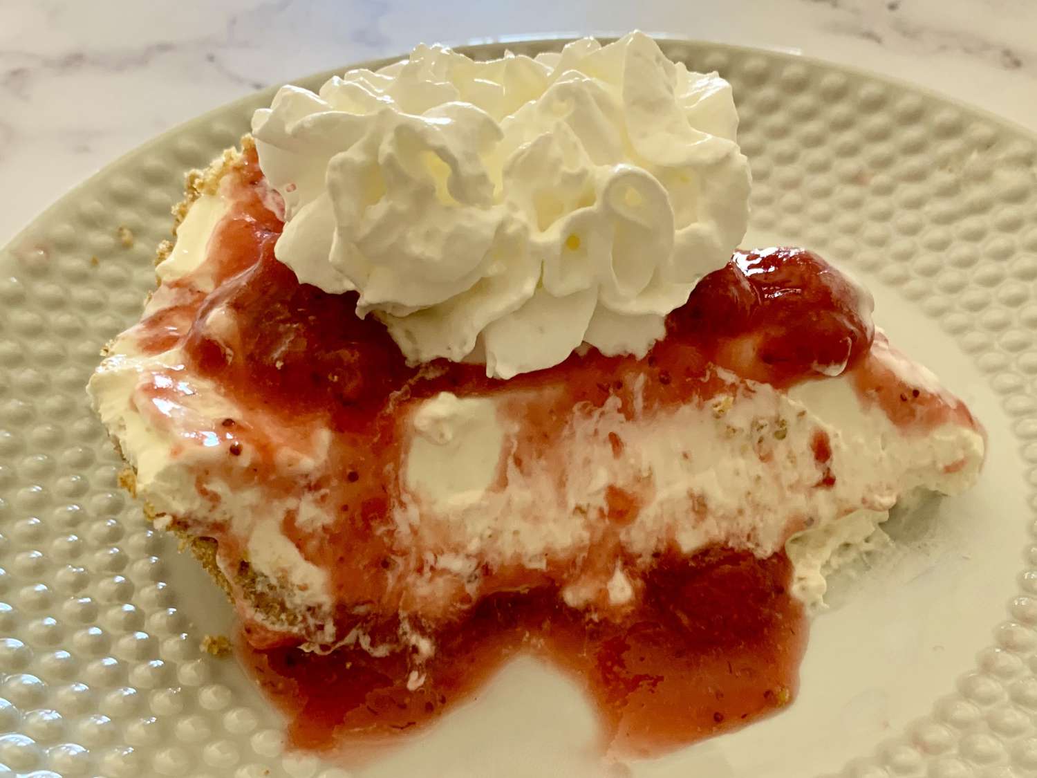 No bake cheesecake with whipped cream and strawberry sauce
