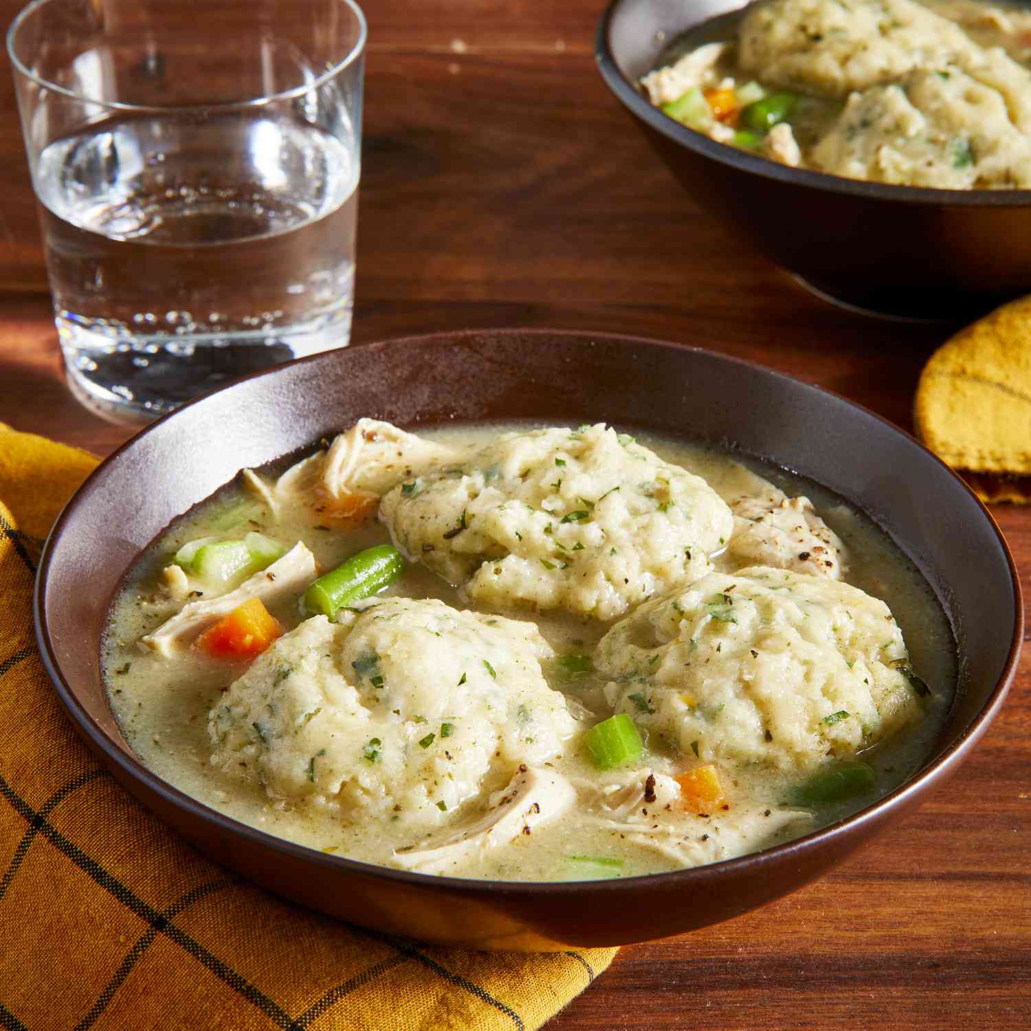 Close up view of Chicken and Dumplings soup in a brown bowl