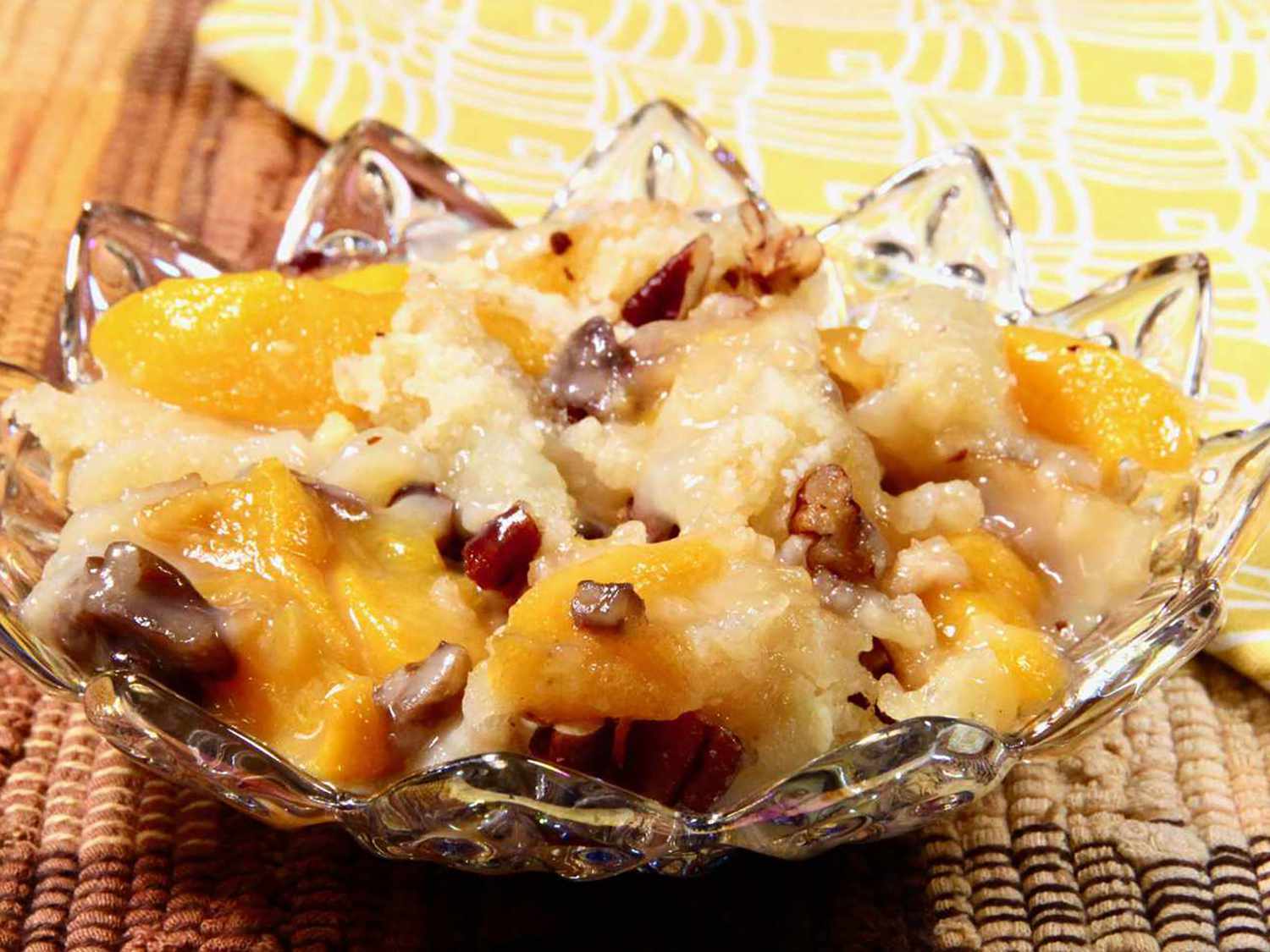 Close up view of Peach Cobbler with Canned Peaches garnished with nuts, in a glass bowl