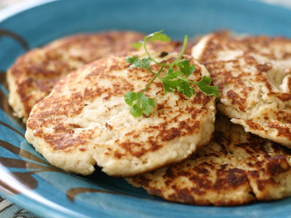 Close up view of Cauliflower Patties garnished with fresh herbs on a blue plate