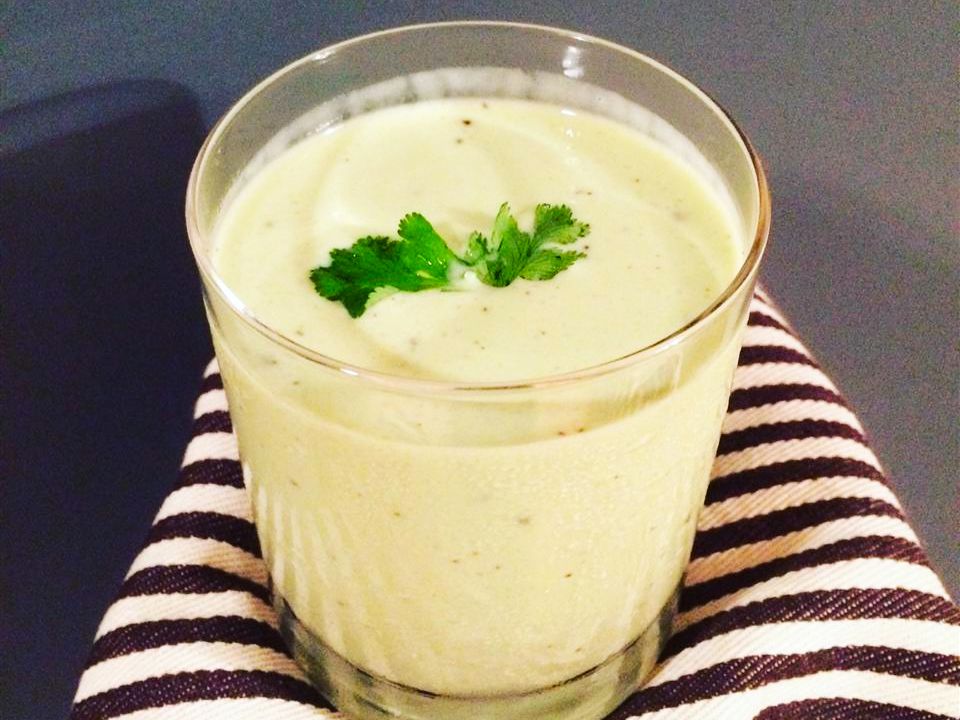 Close up view of a Filipino Avocado Milkshake garnished with fresh herbs in a glass, on a striped kitchen towel