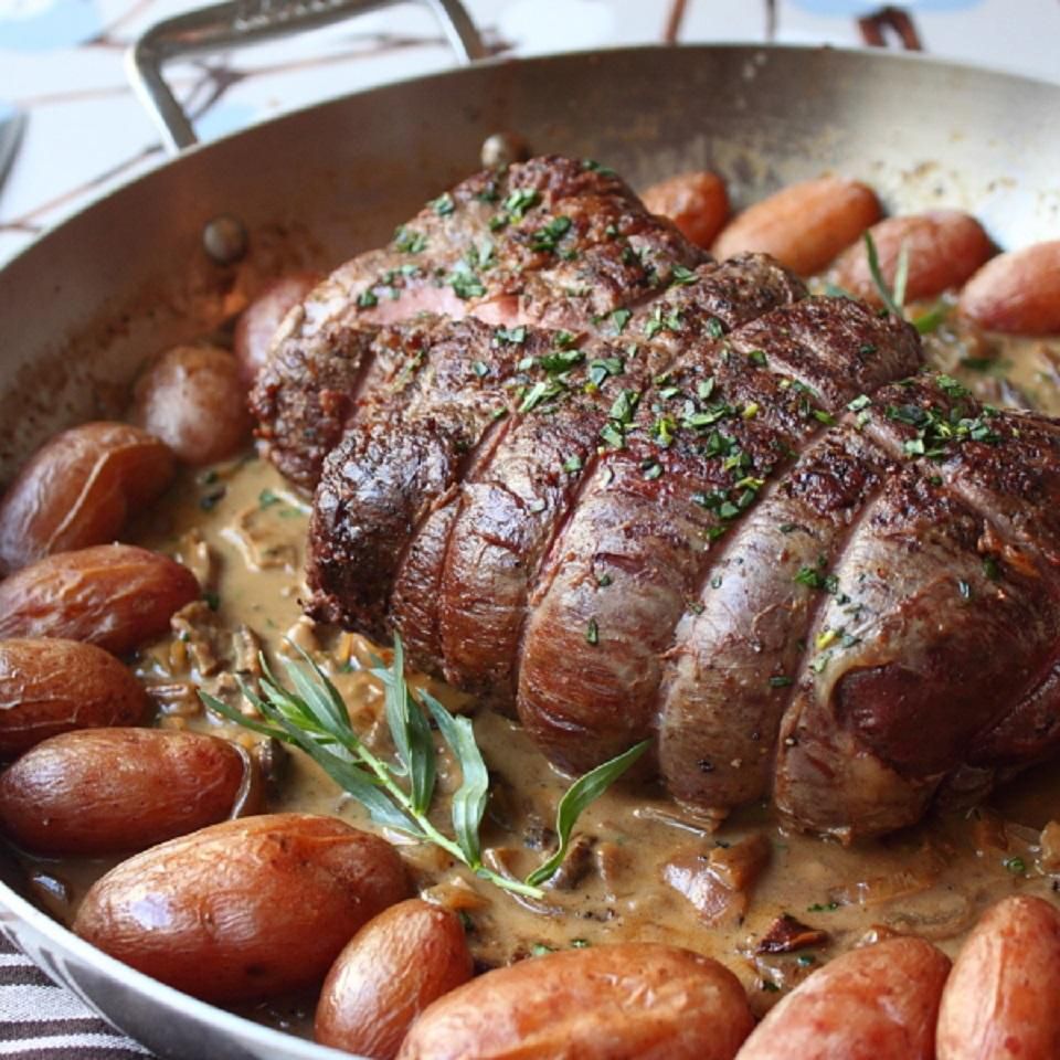 Close up view of Roast Beef Tenderloin in a pan with potatoes and herbs