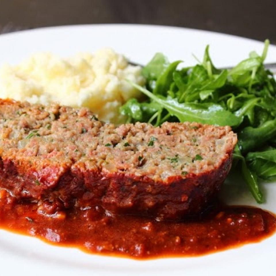 Close up view of Meatball-Inspired Meatloaf served with mashed potatoes and arugula salad on a white plate
