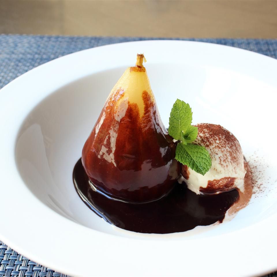 Close up view of Poached Pears Belle Helene garnished with fresh herbs in a white bowl