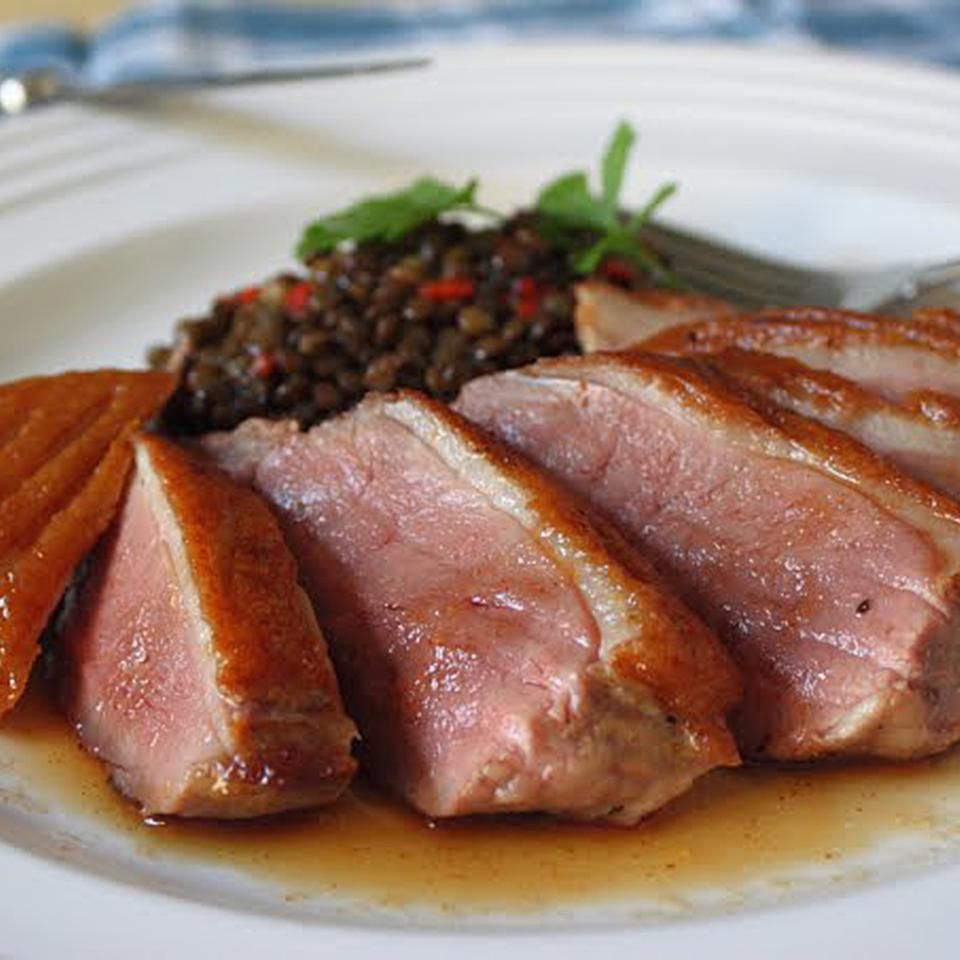 Close up view of sliced Sous Vide Duck Breast on a white plate with grains