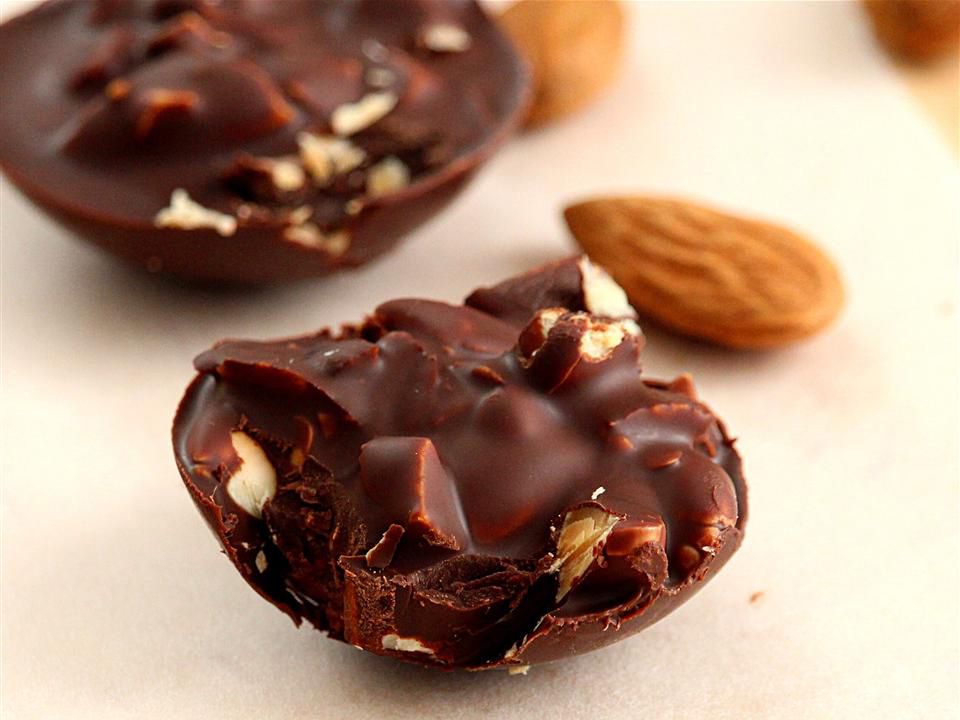 Close up view of Dark Chocolate Almond Rocks and almonds on a white surface