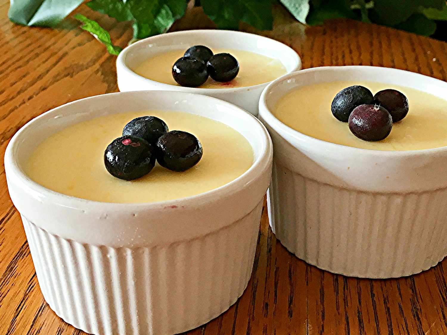 Close up view of Mango Pudding garnished with blueberries in white ramekins