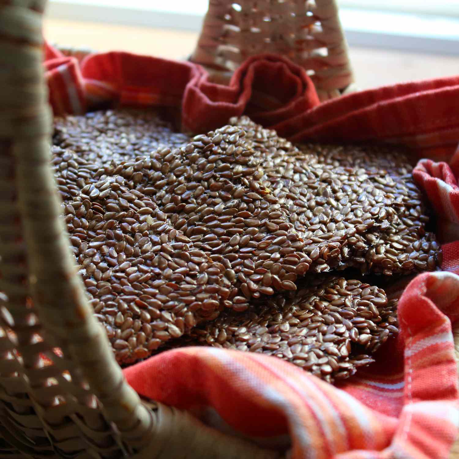 Close up view of Flax Seed Crackers in a kitchen towel lined basket