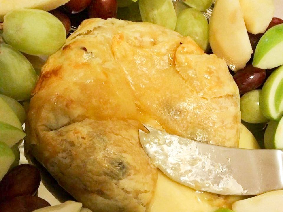 Close up view of Baked Brie en Croute served with green and red grapes, and apples slices