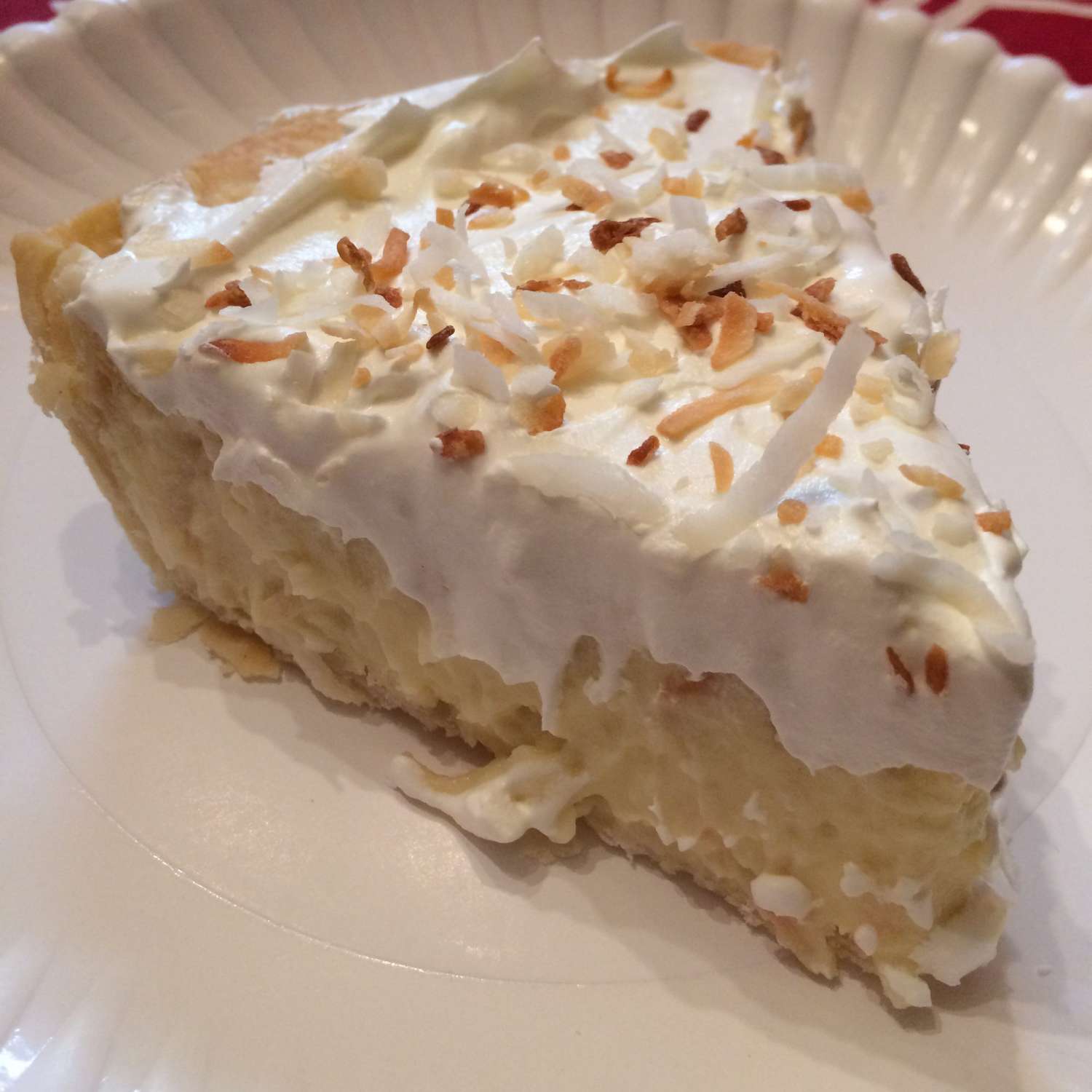 A slice of pie topped with toasted coconut on a white plate