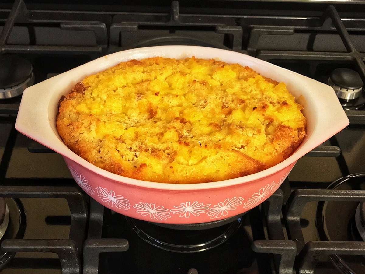 Close up view of a Baked Pineapple Casserole in a red and white baking dish on a stove