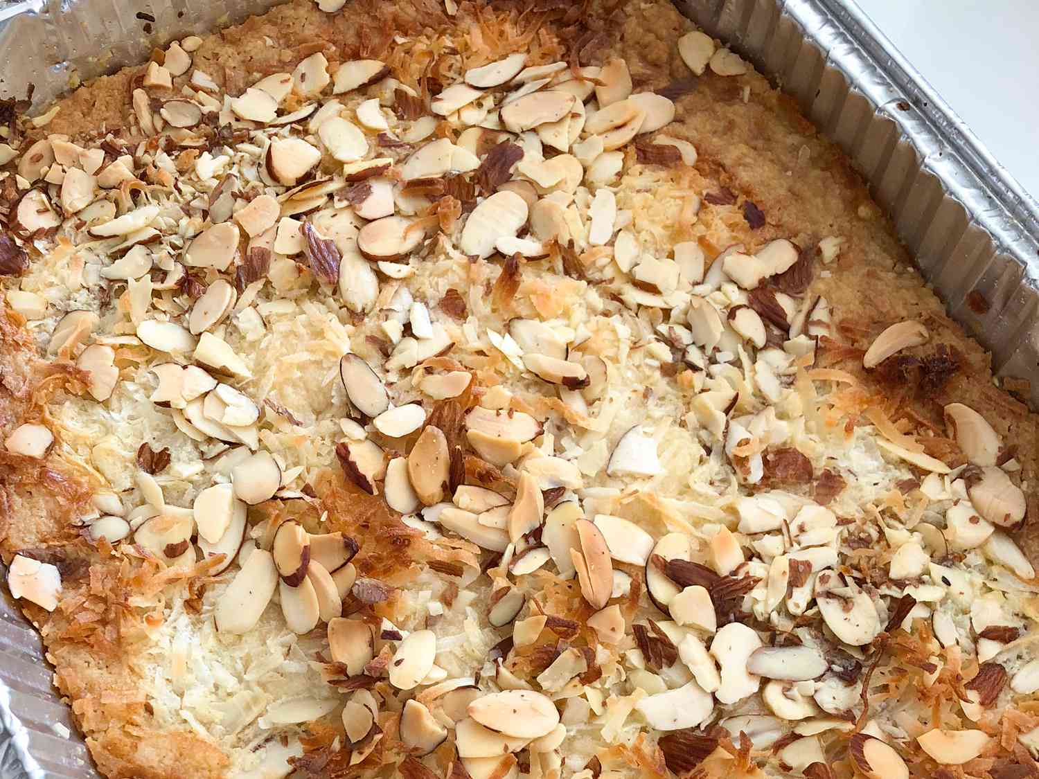 Close up view of Dump Cake garnished with sliced almonds in an aluminum baking dish