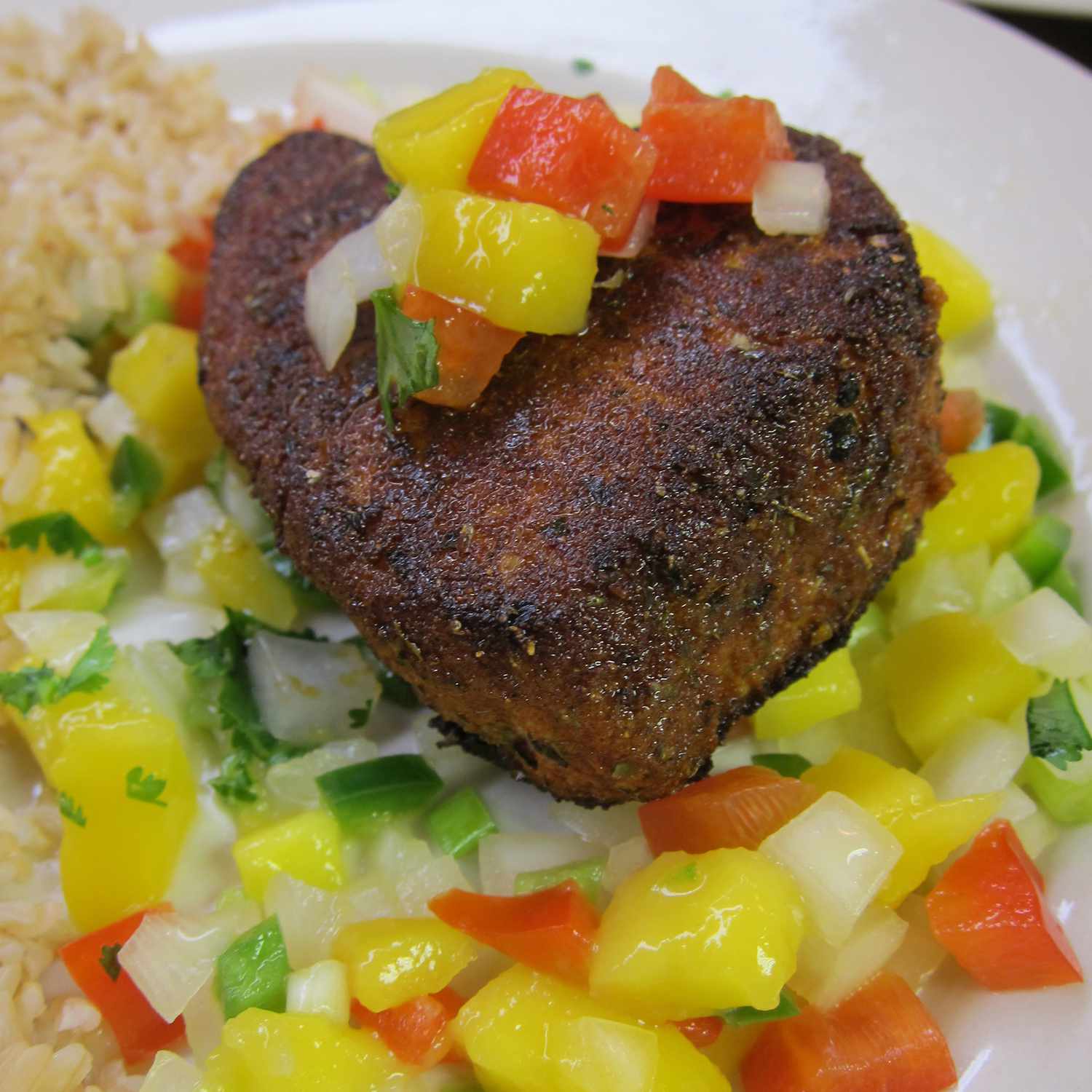 Close up view of a fillet of Blackened Tuna Steaks with Mango Salsa on a white plate