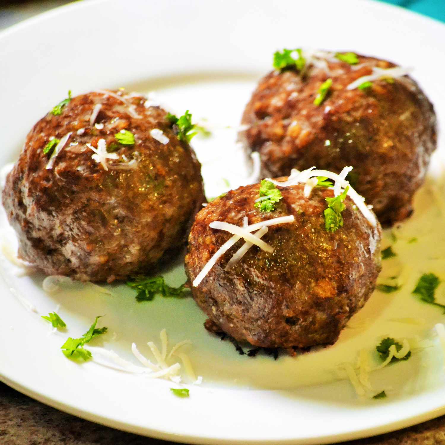 Close up image of Italian baked meatballs with cheese and herbs on a plate