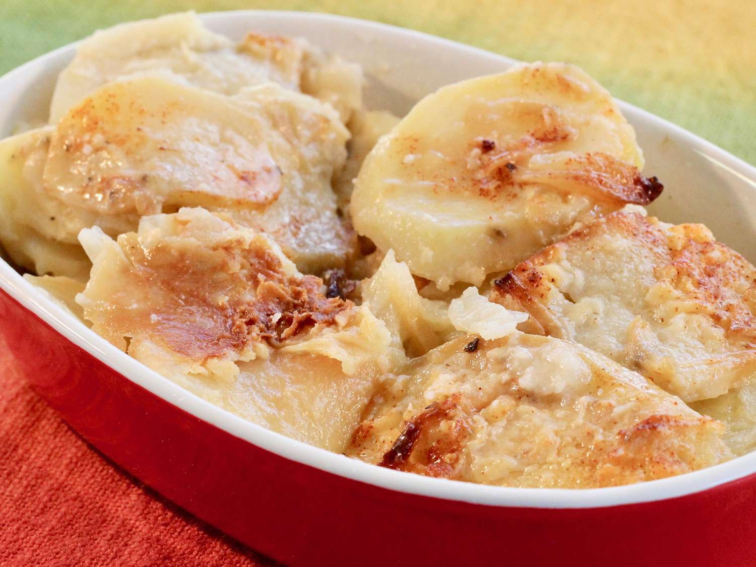 Close up view of Creamy and Crispy Scalloped Potatoes in a red and white baking dish