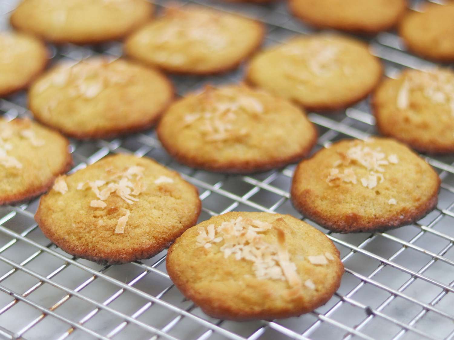 Close up view of Keto Coconut Cookies garnished with coconut on a cooling rack