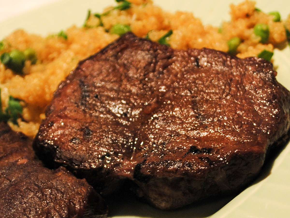 Close up view of Venison Tenderloin served with fried rice on a plate