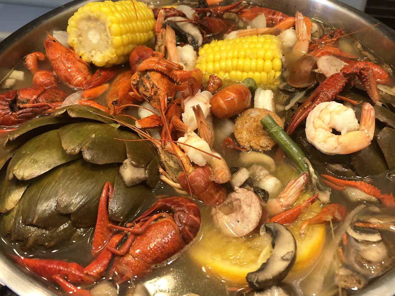 Close up view of Louisiana Crawfish Boil, including crawfish, shrimp, corn, mushrooms, oranges and artichokes