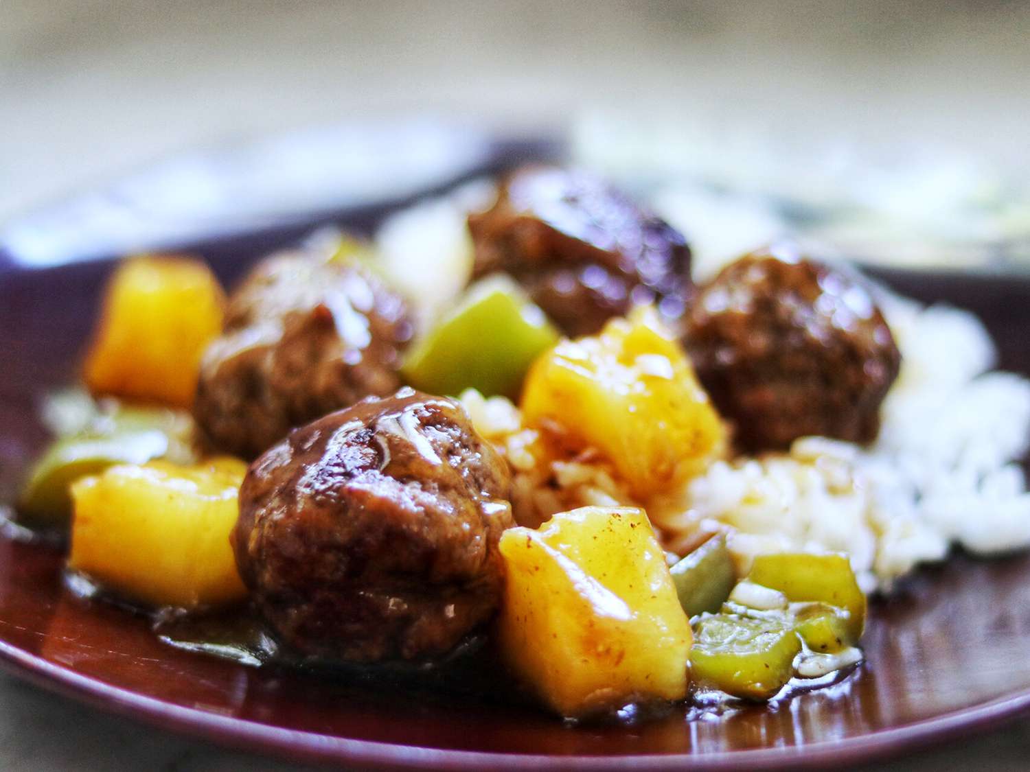 Close up view of Hawaiian Meatballs with pineapple, sauce and white rice on a palte