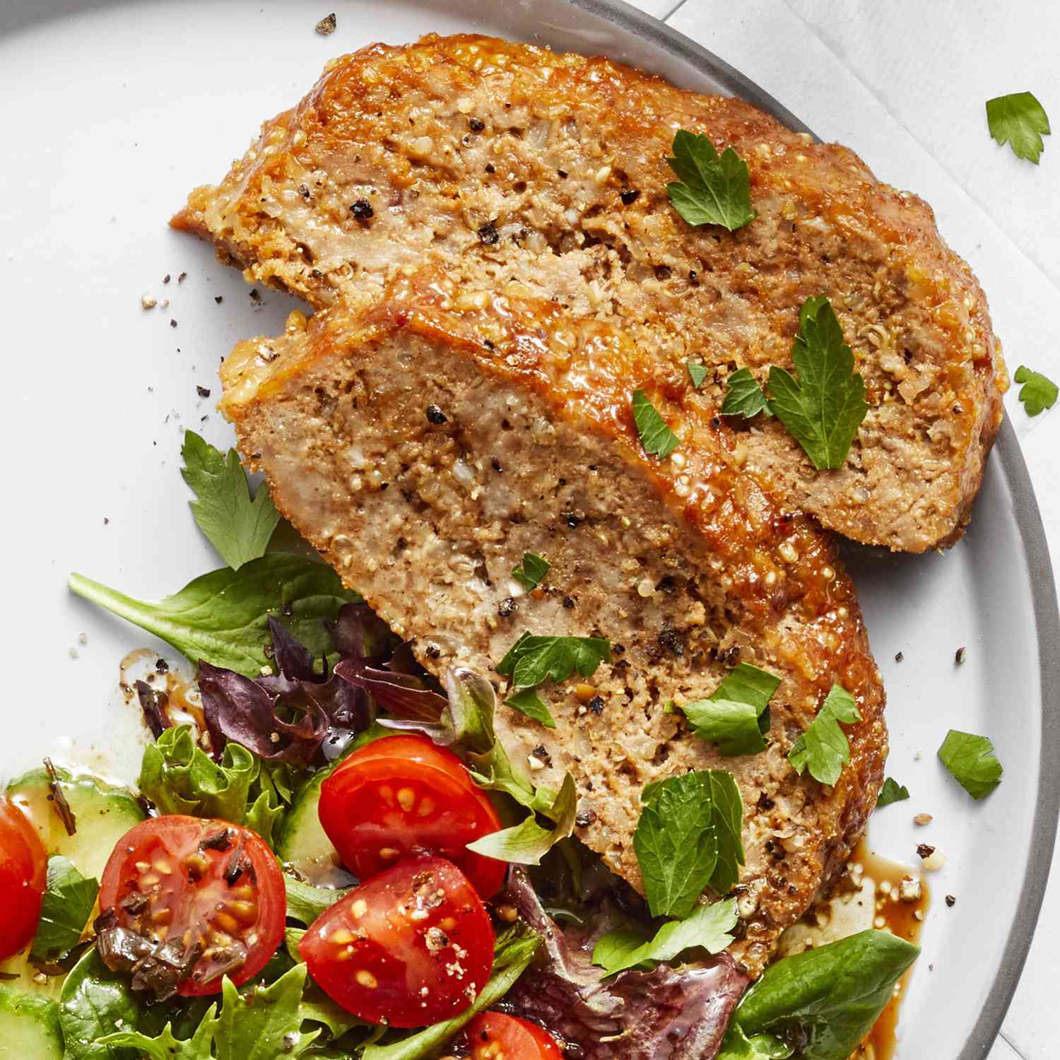 Close up view of slices of Turkey and Quinoa Meatloaf with salad on a white plate