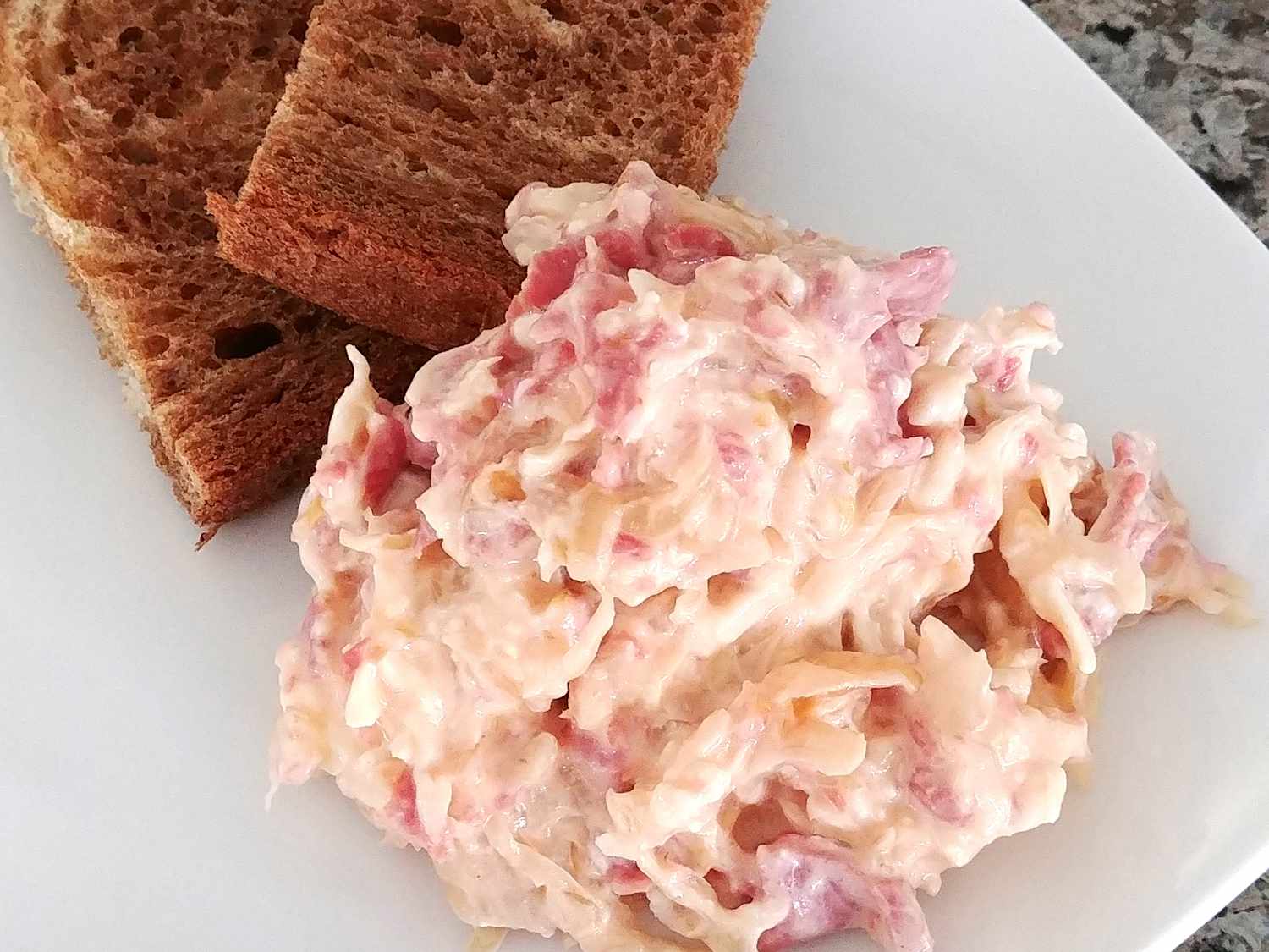 Close up view of Slow Cooker Reuben Dip served with toast on a white plate