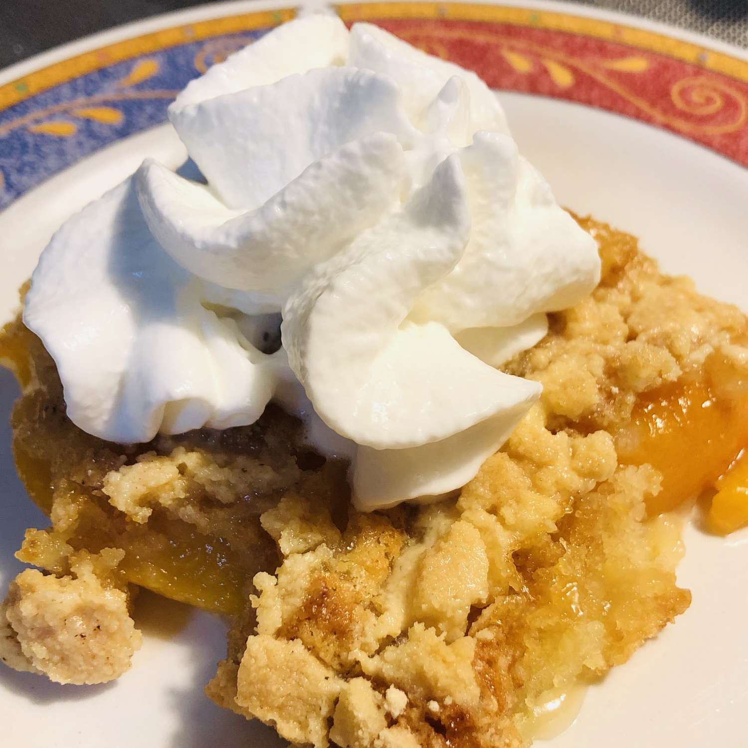 A plate with peach dump cake and whipped cream