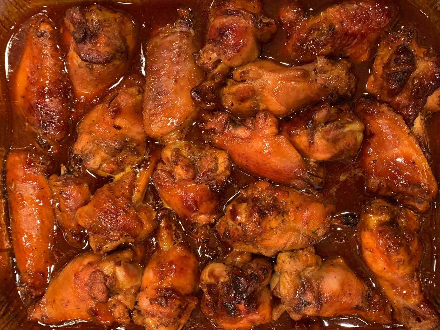 Close up view of Sweet Spicy Wings in sauce in an aluminum baking dish