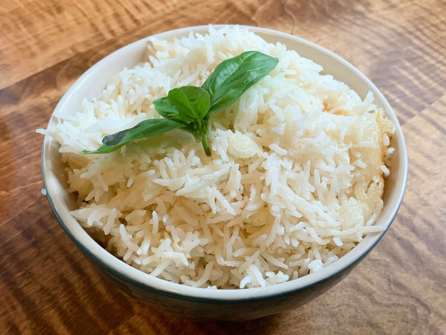 Close up view of Coconut Jasmine Rice in a white bowl garnished with fresh basil