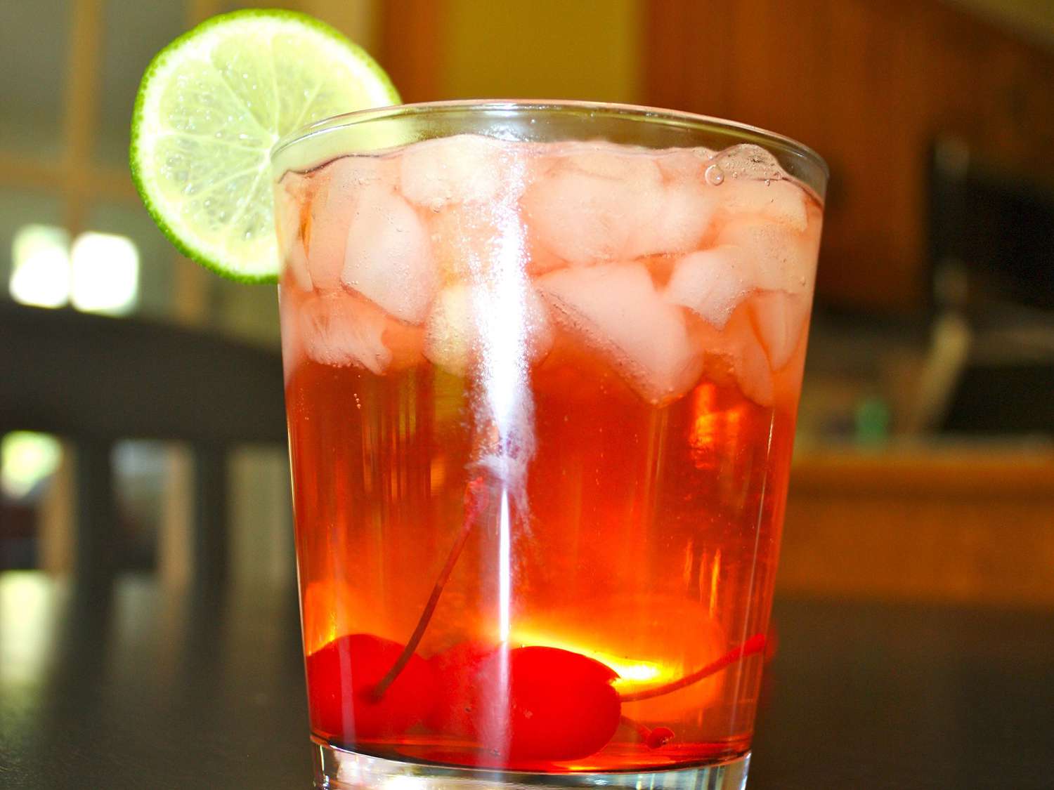 Close up view of Cherry Bomb with ice in a glass, garnished with a lime wheel