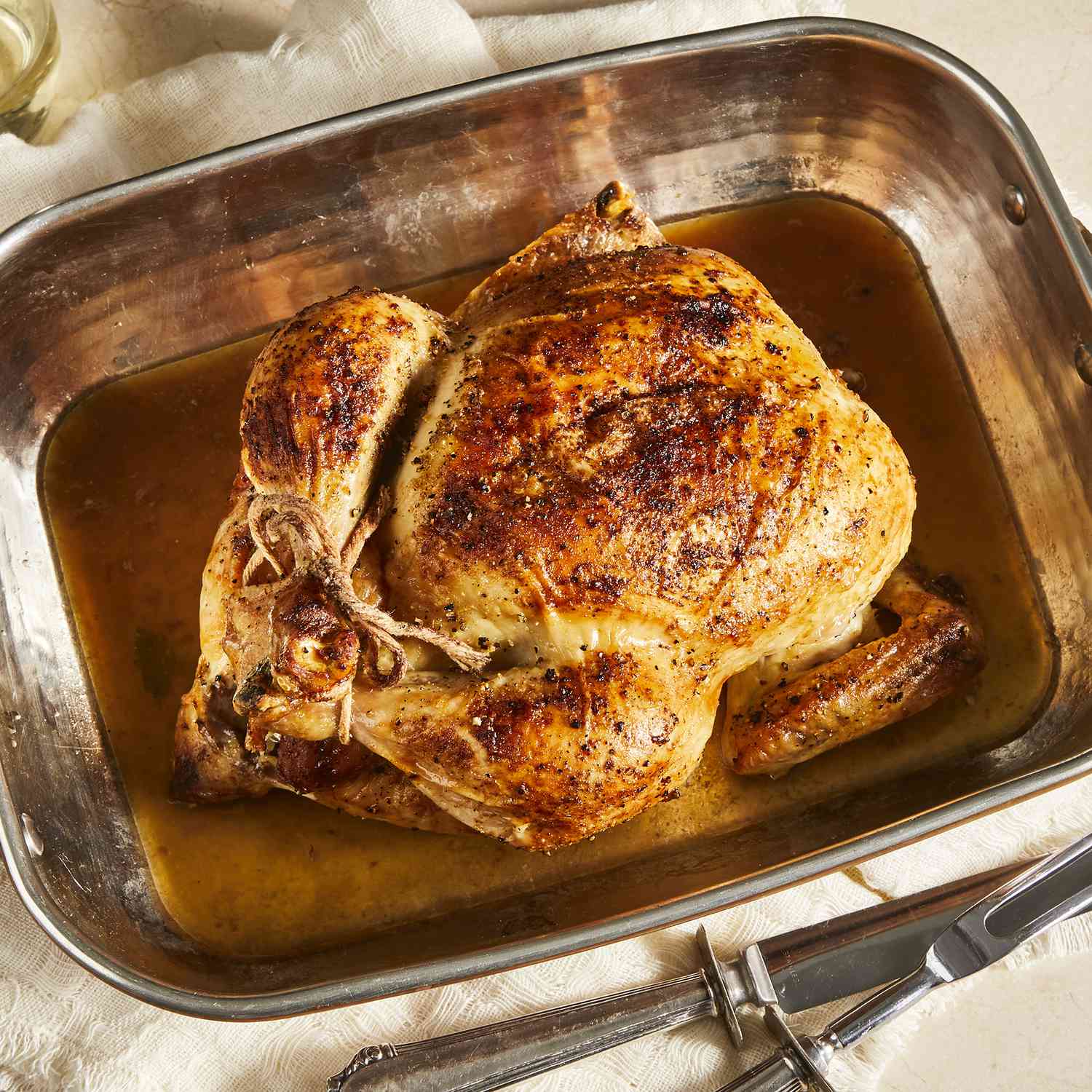 An overhead view of a whole beautiful roasted chicken in a roasting pan.