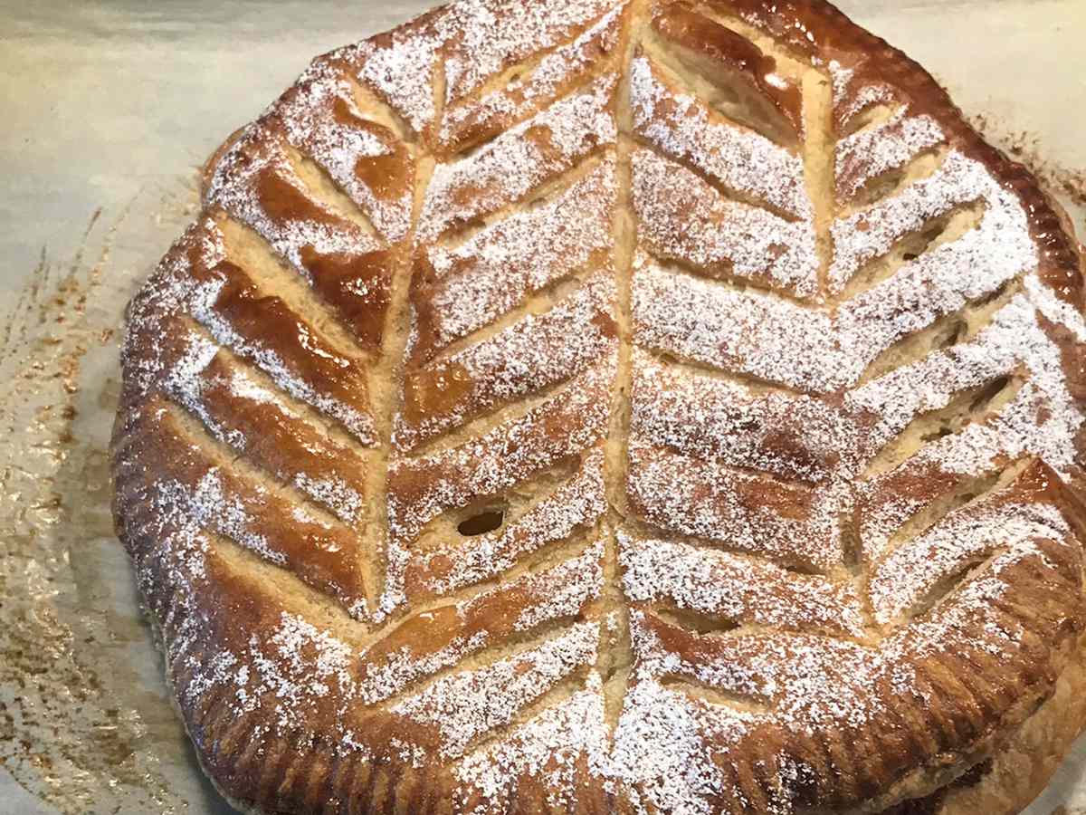 Close up view of a Galette des Rois garnished with powdered sugar on a baking sheet