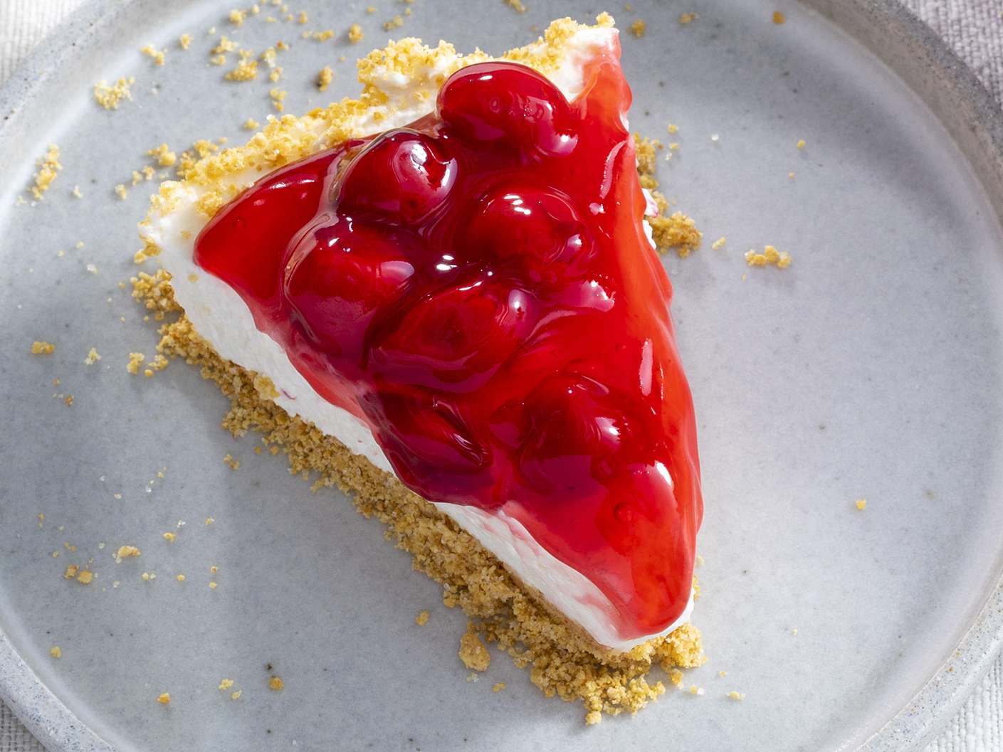 Top-down view of a slice of cherry pie filling-topped cheesecake